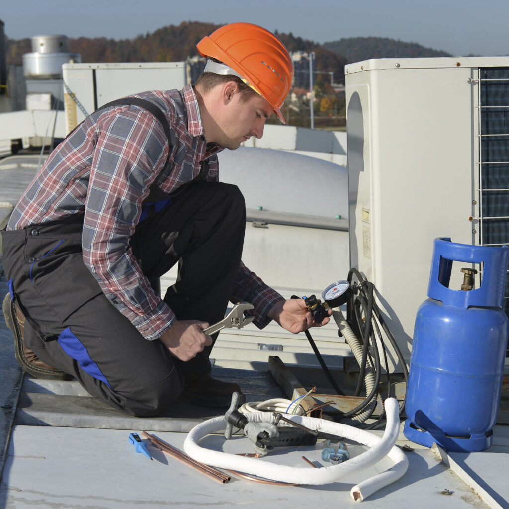 Un ouvrier qui travaille sur le toit pour faire la maintenance de la climatisation