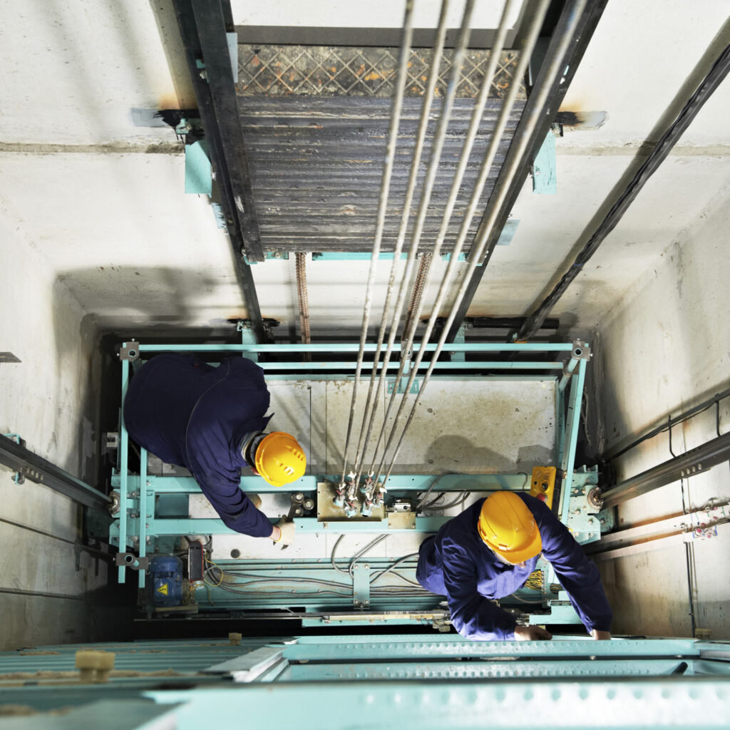 Deux ouvriers qui travaillent dans une cage d'ascenseur